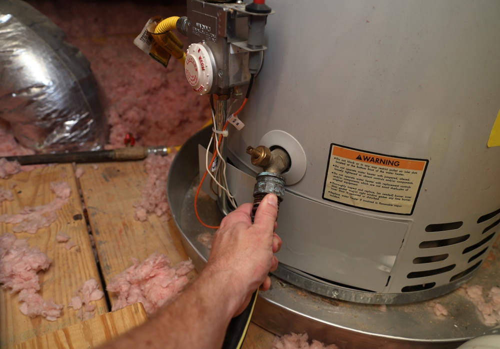 Hand,Attaches,Hose,To,A,Home,Water,Heater,To,Perform